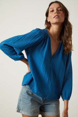 the model is wearing Maggie Cotton Gauze V-Neck Top shorts and a blue blouse.