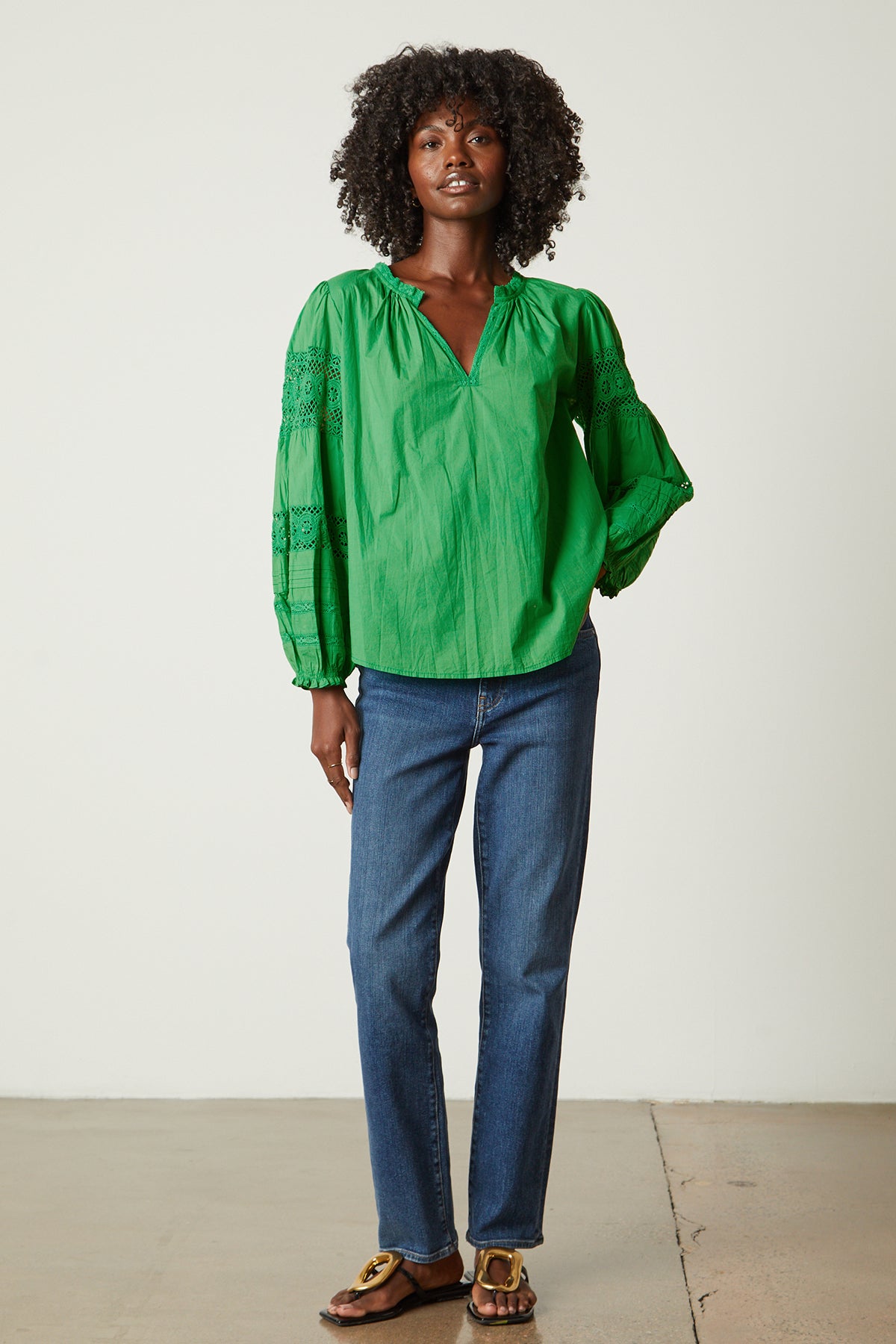   The model is wearing a green Velvet by Graham & Spencer TAYLER COTTON LACE BOHO TOP and jeans. 
