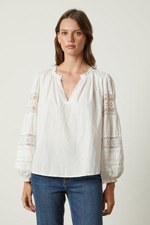 The model is wearing a TAYLER COTTON LACE BOHO TOP by Velvet by Graham & Spencer.