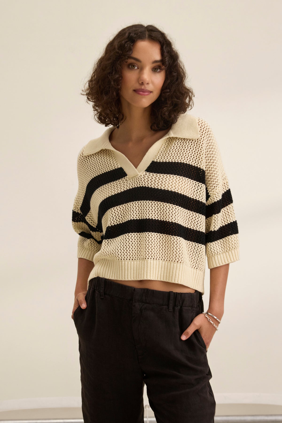 A curly-haired person wears Velvet by Jenny Graham's YORK COTTON CASHMERE MESH SWEATER POLO with black pants, standing against a plain background.-38928816111809