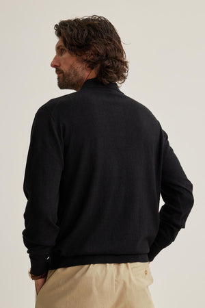 A man with wavy hair is wearing a Velvet by Graham & Spencer MATTEO Cotton Linen Sweater Polo and beige pants, facing away against a plain background.