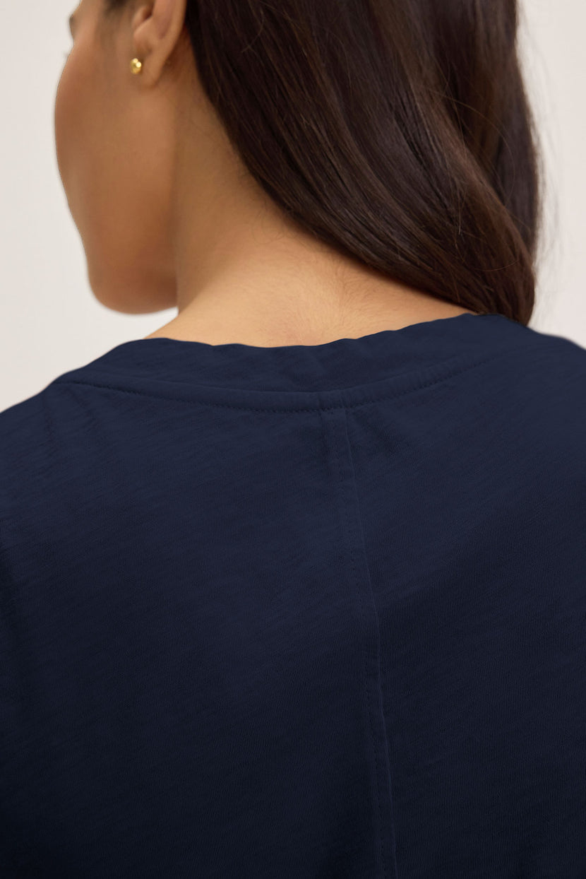 A person with long dark hair is shown from the back wearing Velvet by Graham & Spencer's LILITH TEE, a flattering V-neck crafted from luxurious cotton slub in a dark blue hue.