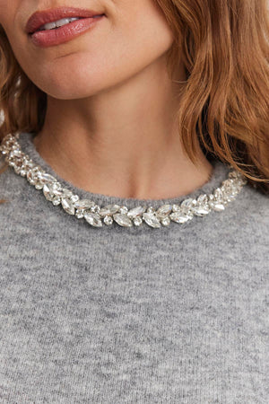 Close-up of a person wearing the LAYTON ALPACA EMBELLISHED SWEATER by Velvet by Graham & Spencer, featuring a rhinestone-adorned neckline.