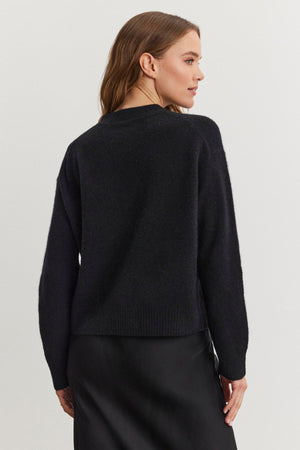 A woman is wearing the MARTI ALPACA EMBELLISHED CARDIGAN by Velvet by Graham & Spencer, paired with a black skirt, and is facing slightly to the side against a plain white background.