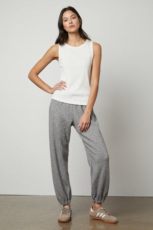 The model is wearing a Velvet by Graham & Spencer Haley Double Knit Sweatpant, white tank top, and engaging in leisure activities.