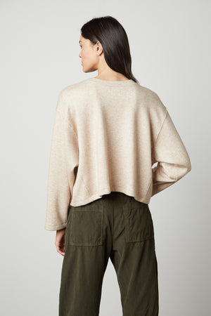 The back view of a woman wearing an oversized beige NIA DOUBLE KNIT CROPPED CREW sweater and olive pants, exuding style and comfort. (Brand Name: Velvet by Graham & Spencer)