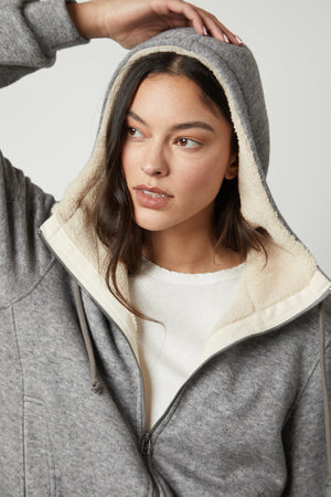 A woman wearing a Velvet by Graham & Spencer OCTAVIA DOUBLE KNIT ZIP UP HOODIE with a sherpa lining.