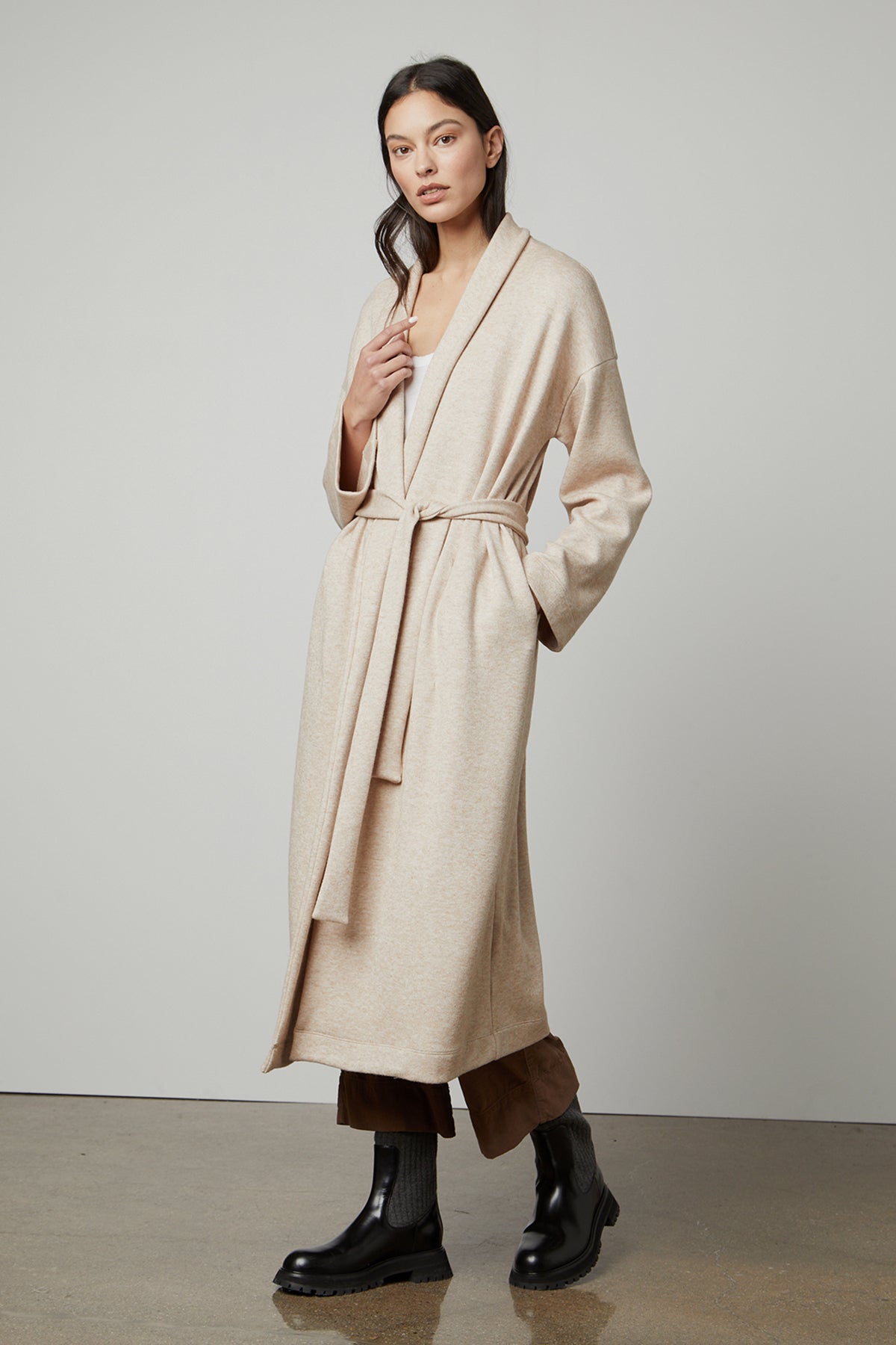  The model is wearing a cozy fabric beige Patricia Double Knit Duster Cardigan with a belt by Velvet by Graham & Spencer. 