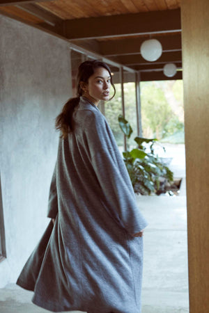 A woman in a cozy grey Velvet by Graham & Spencer Patricia Double Knit Duster Cardigan walking down a hallway.