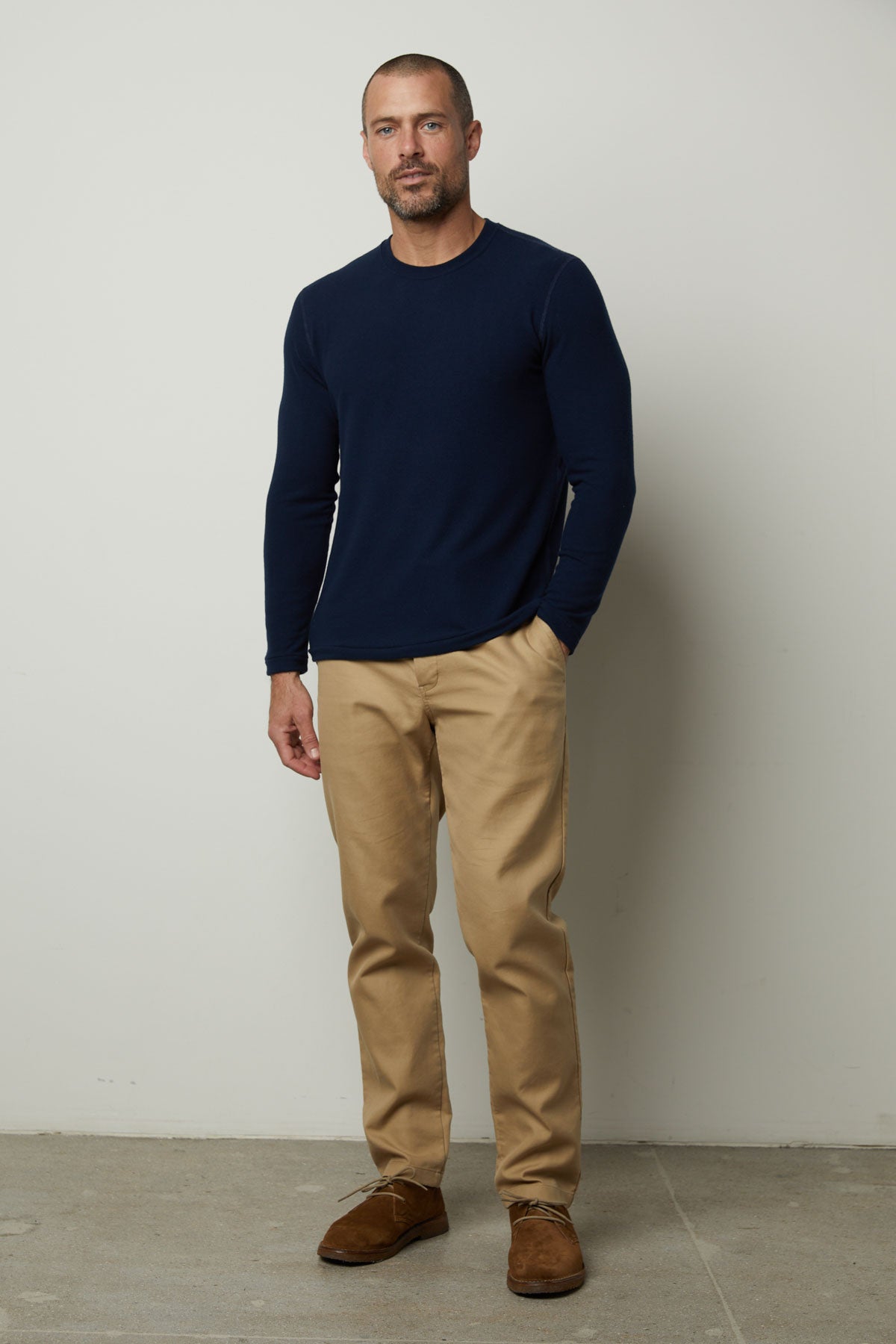   A man wearing a Velvet by Graham & Spencer BECKER COZY JERSEY CREW sweater and tan pants. 