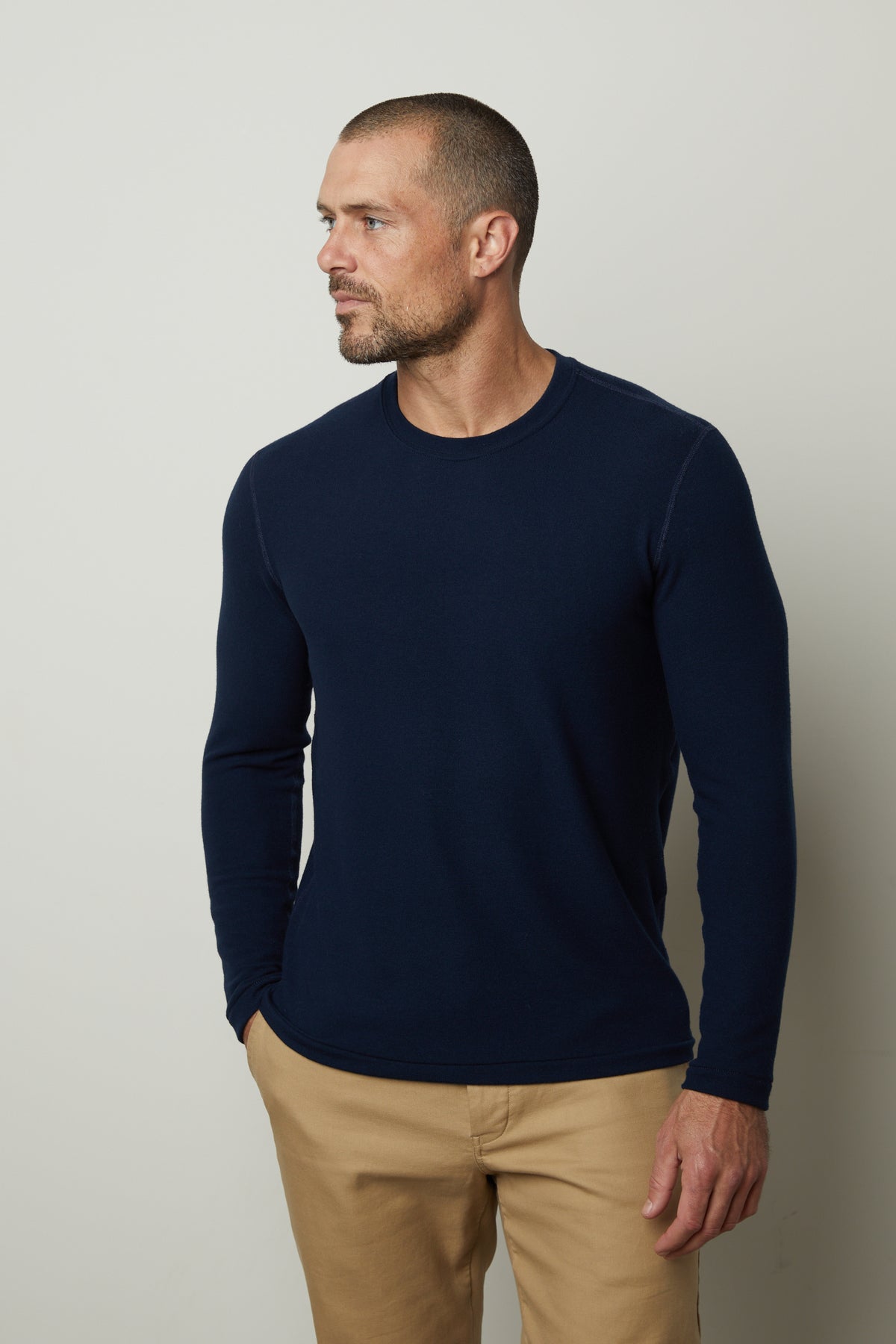   A man wearing a Velvet by Graham & Spencer's BECKER COZY JERSEY CREW navy crew neck sweater and cozy khaki pants. 