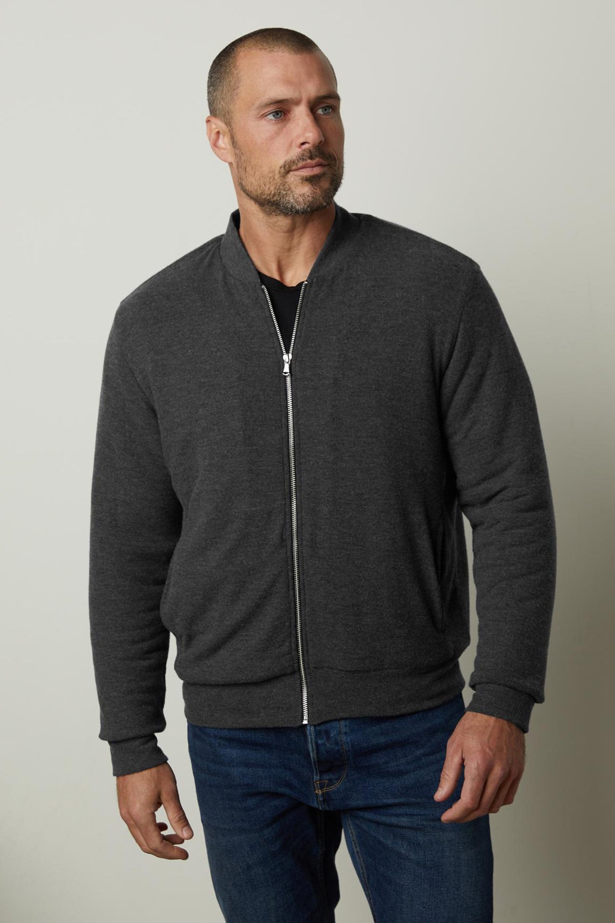   A man wearing a cozy sherpa-lined MILES ZIP-UP JACKET by Velvet by Graham & Spencer and jeans. 