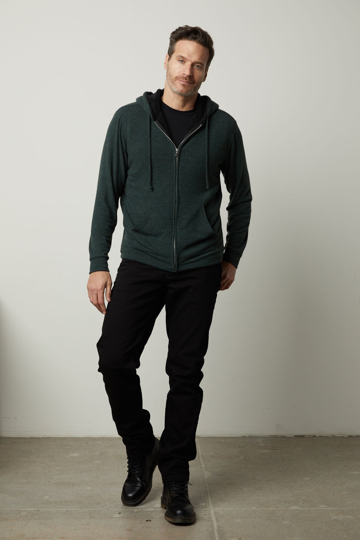 A man wearing a Velvet by Graham & Spencer SALVADORE SHERPA LINED HOODIE with an adjustable drawstring hood and black pants.-35605834072257