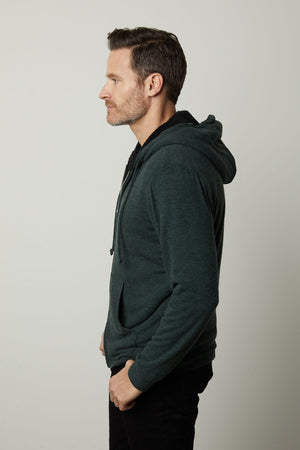 A man wearing a Velvet by Graham & Spencer Salvadore Sherpa lined green hoodie and black pants.