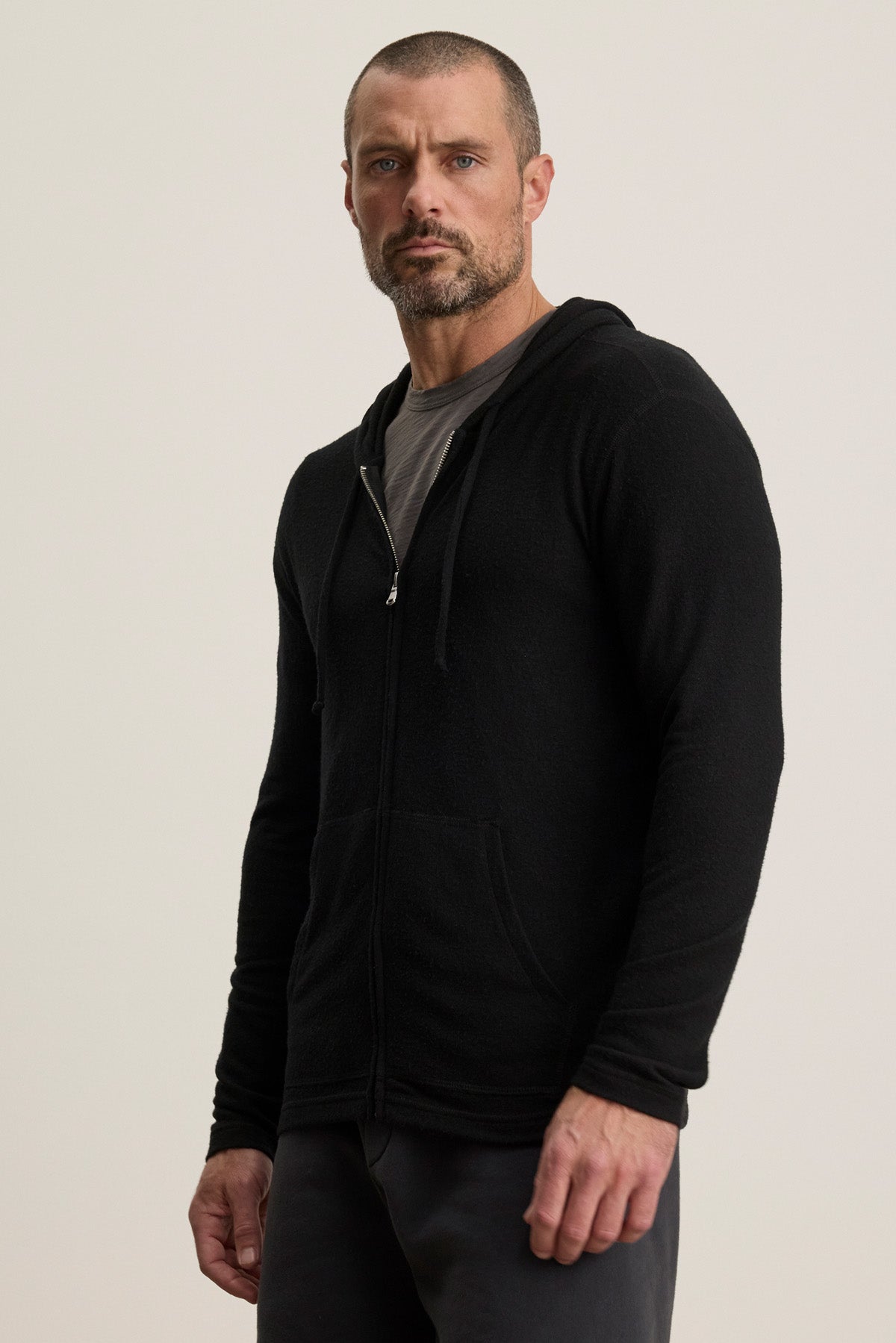 A man with a trimmed beard wears the Velvet by Graham & Spencer LOUDON HOODIE over a gray t-shirt, standing against a plain light background.