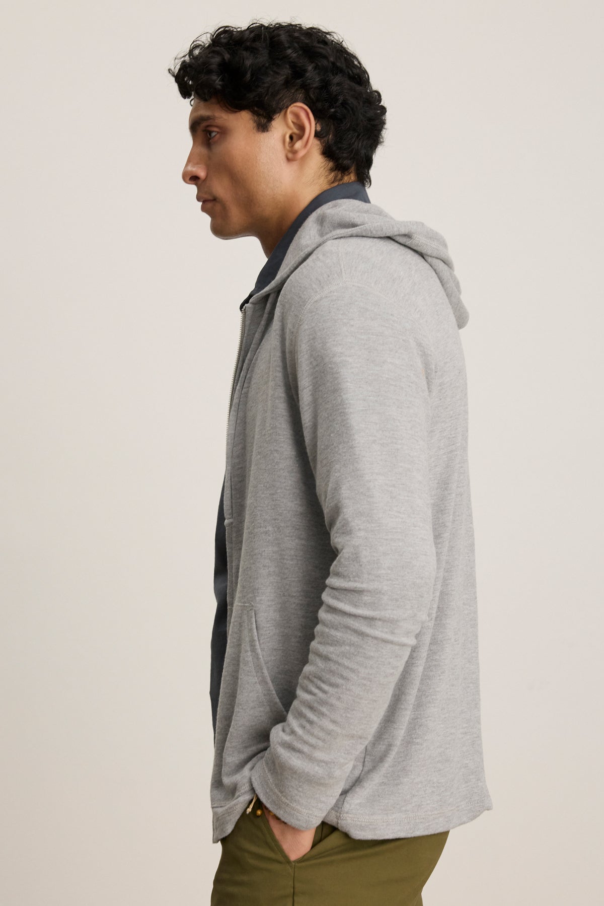A man in a relaxed fit, gray LOUDON HOODIE by Velvet by Graham & Spencer and olive green pants stands in profile against a plain light background.-39680474742977