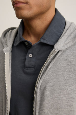 Close-up of a person wearing the LOUDON HOODIE by Velvet by Graham & Spencer in light gray, layered over a dark blue polo. The image shows the relaxed fit and soft triblend jersey fabric, focusing on the lower face and upper torso.