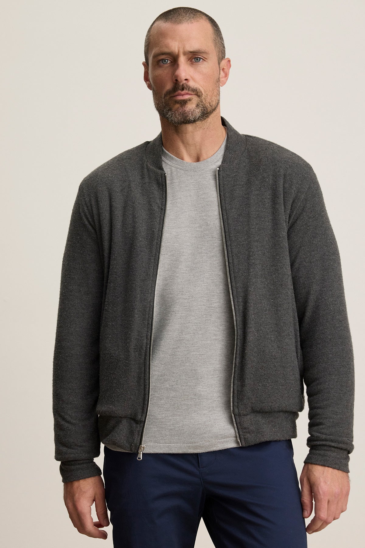 A man with short hair and a beard wears the Velvet by Graham & Spencer MILES JACKET over a light gray shirt and navy pants, standing against a plain light background.-40247444897985