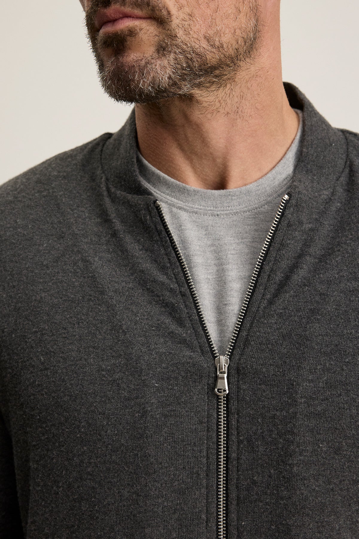 Close-up of a man wearing the MILES JACKET by Velvet by Graham & Spencer—a casual jacket with a soft knit shell—over a light gray t-shirt, showing only his lower face and upper torso.-40247445881025