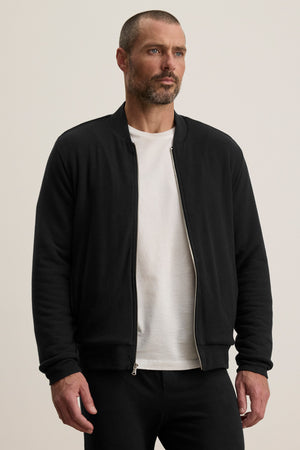 A man wearing a white t-shirt and the MILES JACKET by Velvet by Graham & Spencer stands facing forward against a plain, light-colored background.