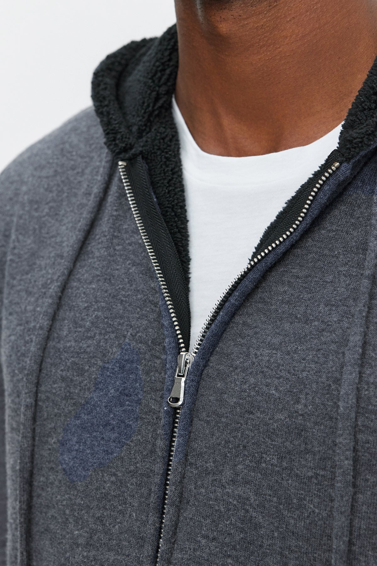   Close-up of a person wearing the SALVADORE HOODIE, an ultra-soft cozy jersey grey full-zip hoodie with a black-lined hood over a white shirt from Velvet by Graham & Spencer. 