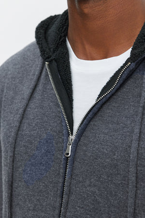 Close-up of a person wearing the SALVADORE HOODIE, an ultra-soft cozy jersey grey full-zip hoodie with a black-lined hood over a white shirt from Velvet by Graham & Spencer.