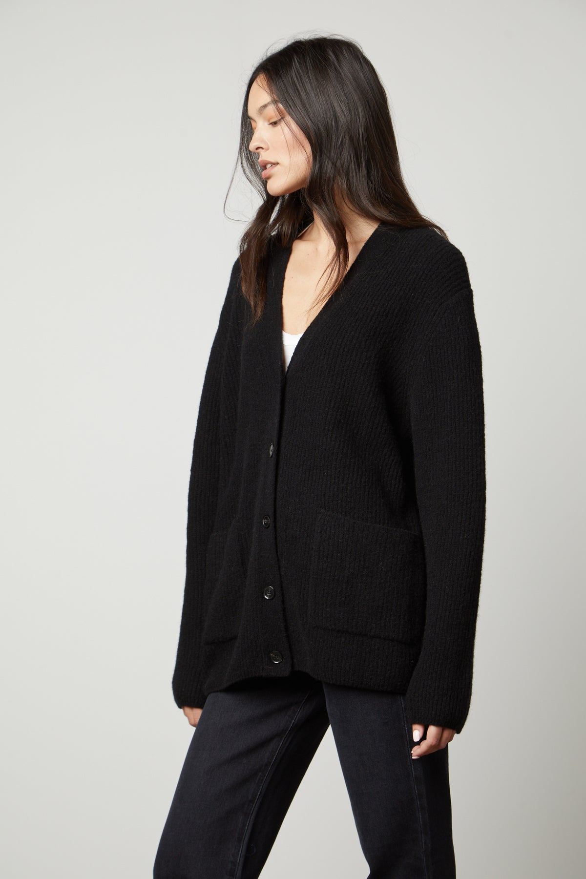 A woman wearing a black Velvet by Graham & Spencer BRITT OVERSIZED CARDIGAN and jeans.-26897709433025