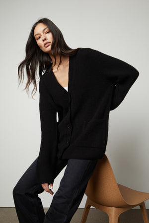 The model is wearing a Velvet by Graham & Spencer BRITT OVERSIZED CARDIGAN and jeans.