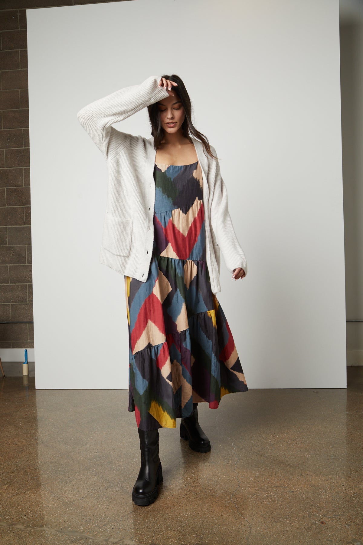   A woman wearing a colorful dress and a Velvet by Graham & Spencer BRITT OVERSIZED CARDIGAN. 