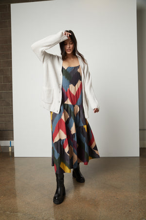 A woman wearing a colorful dress and a Velvet by Graham & Spencer BRITT OVERSIZED CARDIGAN.