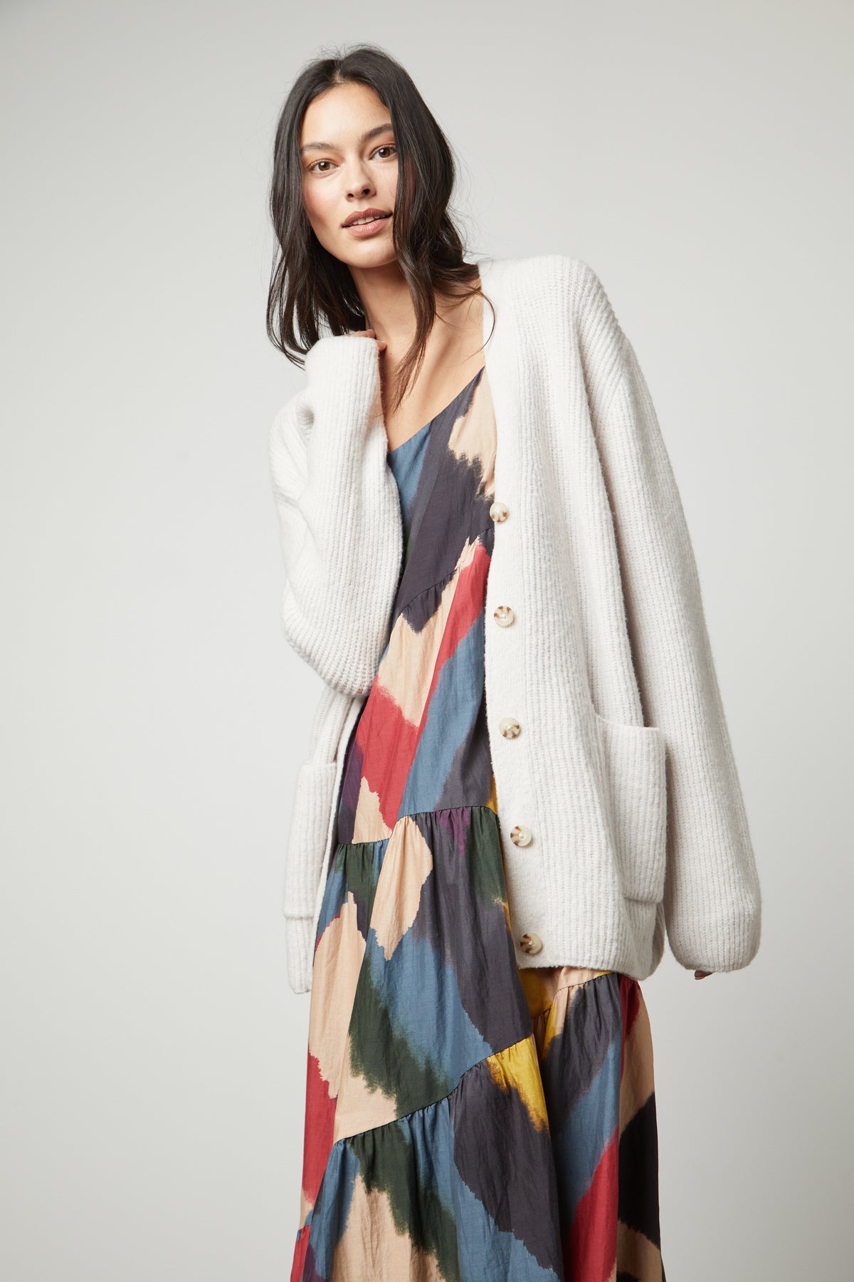   The model is wearing a multicolored dress and a Velvet by Graham & Spencer BRITT OVERSIZED CARDIGAN. 