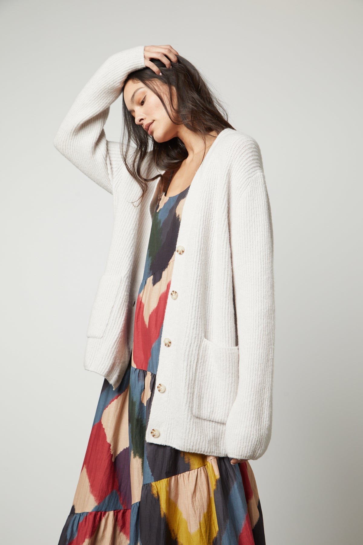   The model is wearing a white Velvet by Graham & Spencer BRITT OVERSIZED CARDIGAN and a multicolored dress. 