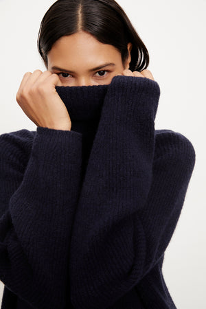 A woman in a Velvet by Graham & Spencer JUDITH turtleneck sweater, made of a wool blend, is cozily dressed.