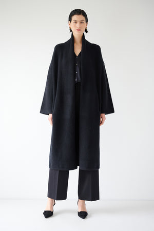 A woman donning a black Carmel Coat by Velvet by Jenny Graham and wool pants.