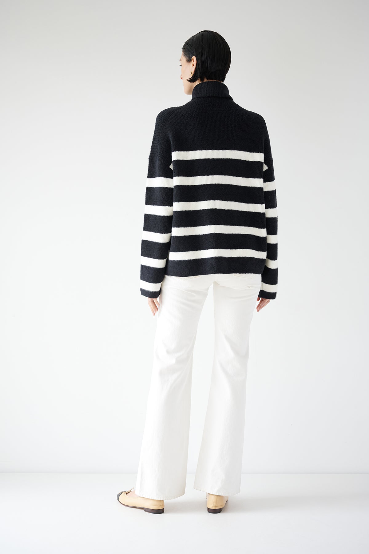  The back view of a woman wearing an oversized ENCINO SWEATER in a black and white striped pattern, by Velvet by Jenny Graham. 