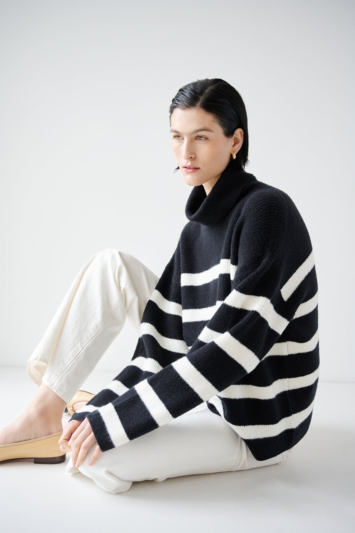   A model wearing the Velvet by Jenny Graham ENCINO sweater, an oversized black and white striped turtleneck sweater in a wool blend fabric. 
