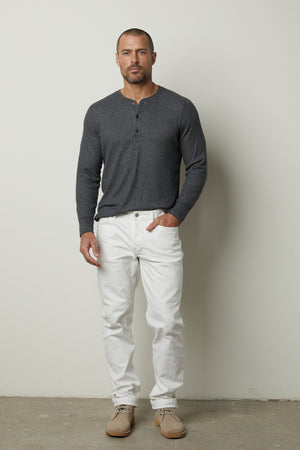 A man wearing a grey sweater with an ANTHONY THERMAL HENLEY by Velvet by Graham & Spencer and white pants.