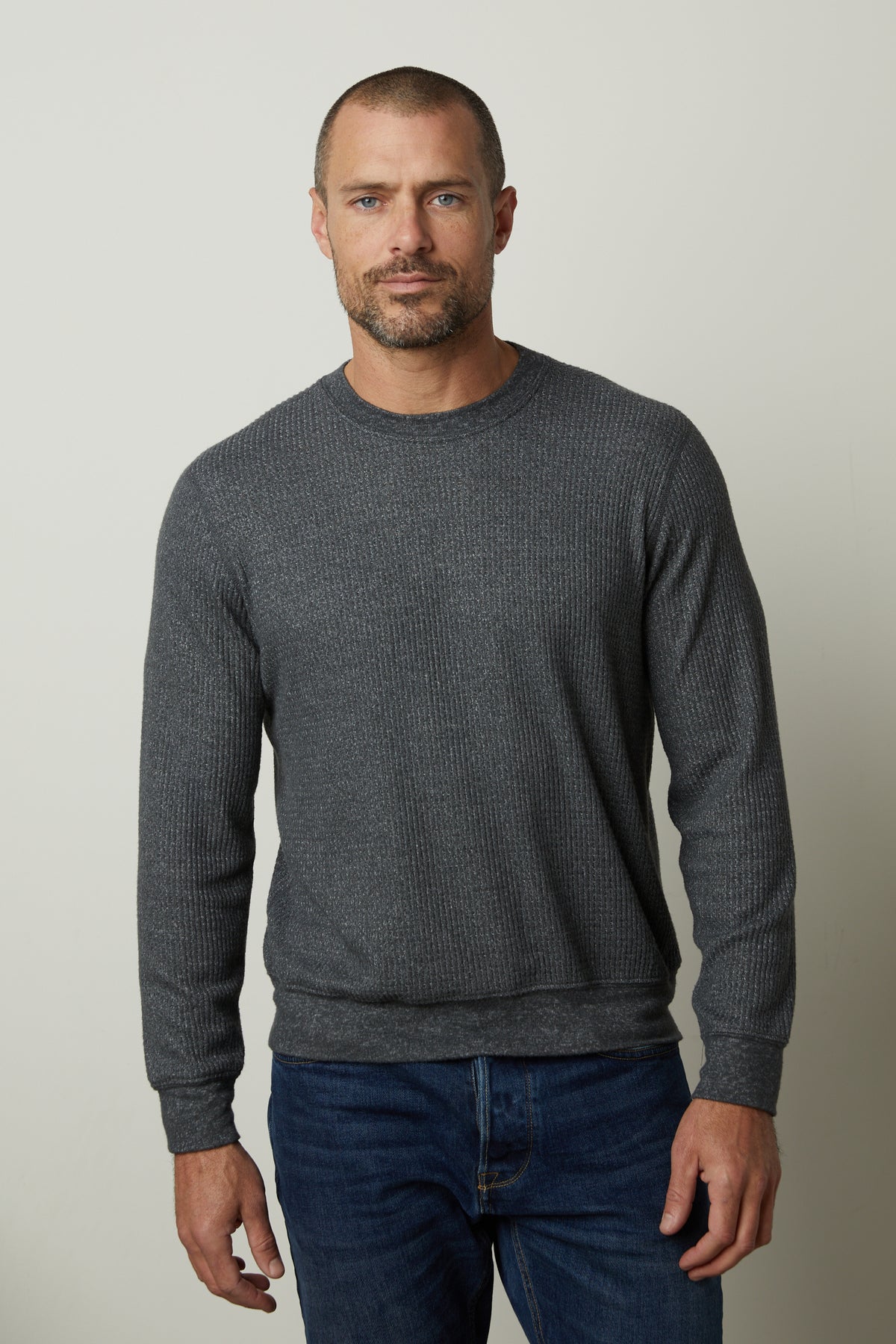 A man wearing a Velvet by Graham & Spencer PONCHO THERMAL CREW sweater and jeans, perfect for cooler days, featuring a crew neck style in premium thermal knit.-35547551465665