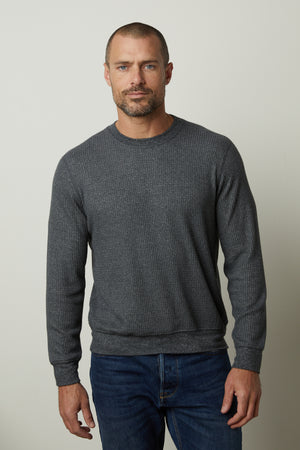 A man wearing a Velvet by Graham & Spencer PONCHO THERMAL CREW sweater and jeans, perfect for cooler days, featuring a crew neck style in premium thermal knit.