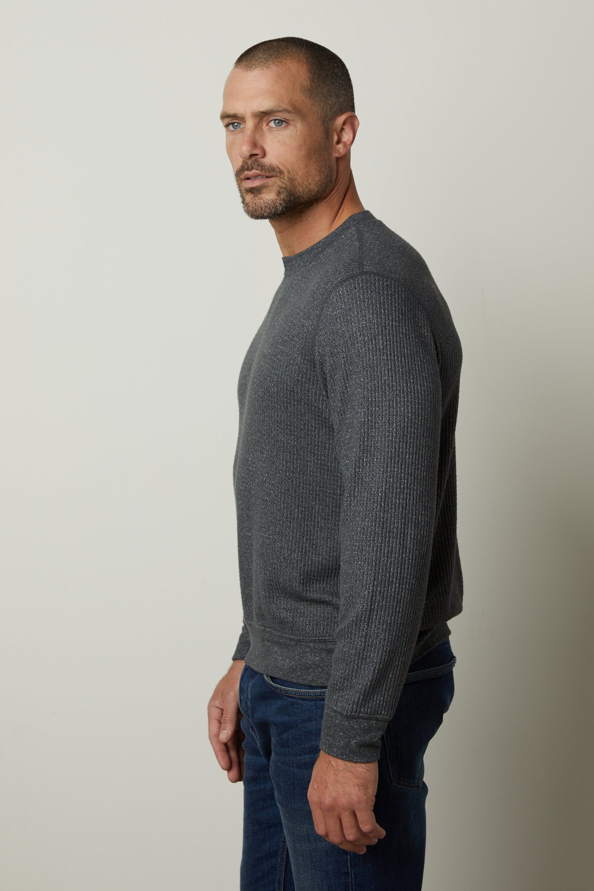   A man wearing a grey Velvet by Graham & Spencer sweater and jeans is perfect for cooler days, especially with the PONCHO THERMAL CREW style. 