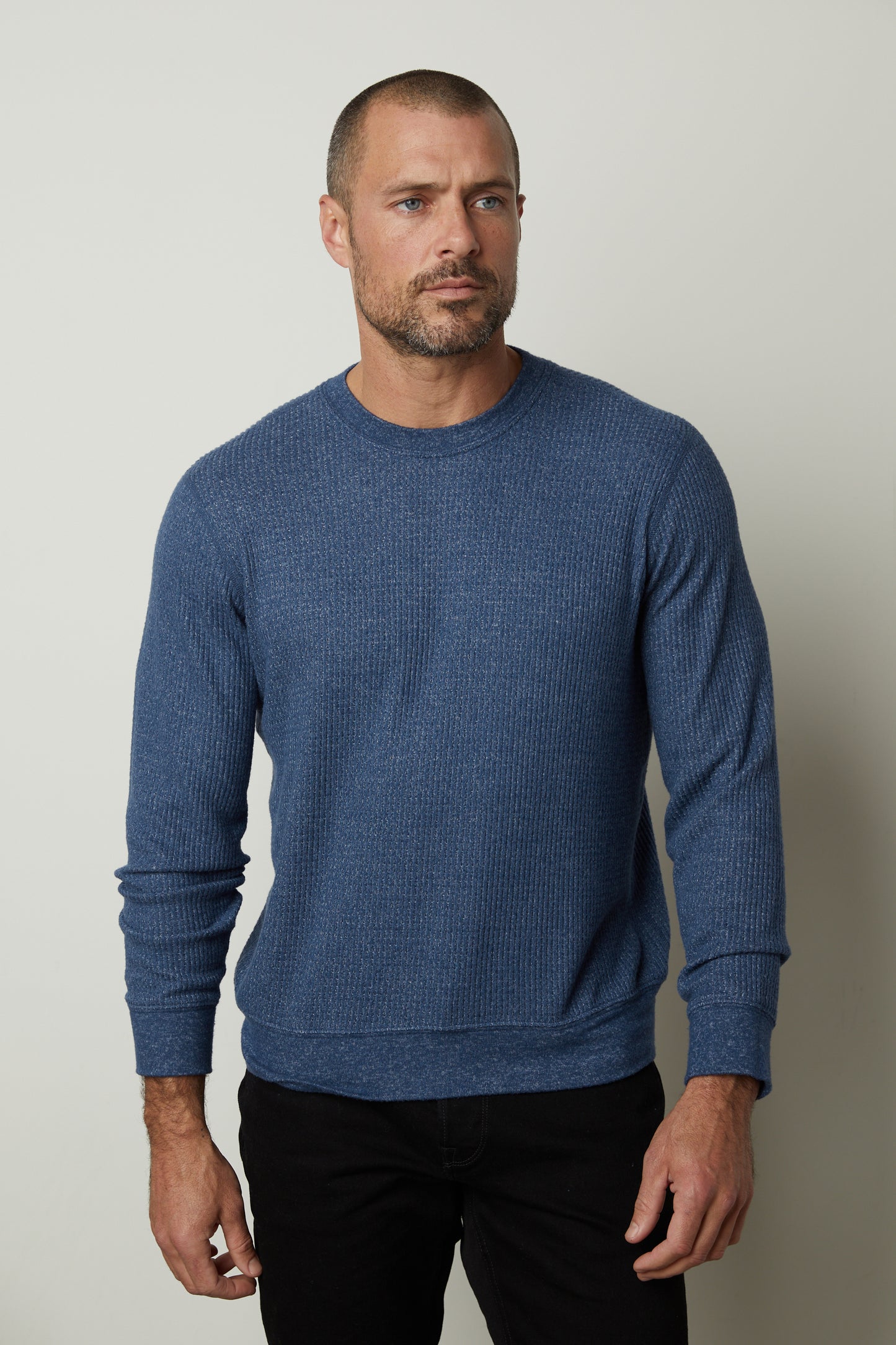 A man wearing a Velvet by Graham & Spencer PONCHO THERMAL CREW sweater and black pants, perfect for cooler days.-35472111567041