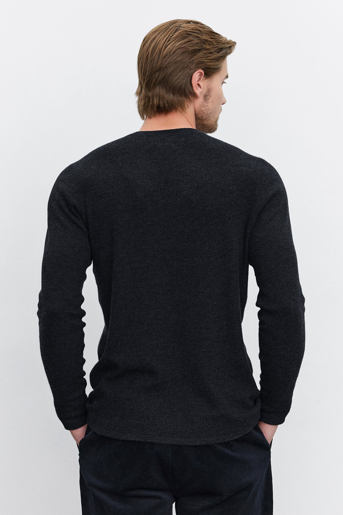 A person with light brown hair stands facing away, wearing a Velvet by Graham & Spencer AMBROSE HENLEY shirt in dark gray with a three-button placket and black pants, against a plain white background.-37893849120961