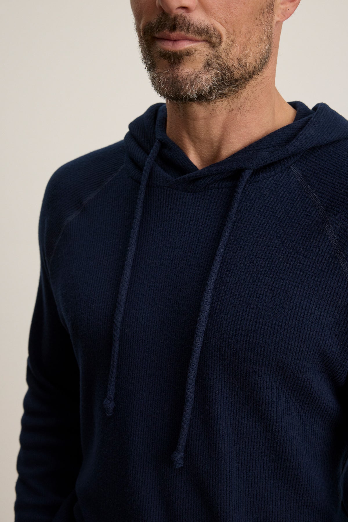 A man models the ROMEO HOODIE by Velvet by Graham & Spencer—a dark blue, relaxed-fit pullover—shown from shoulders to just above the mouth against a light background.-39957110718657