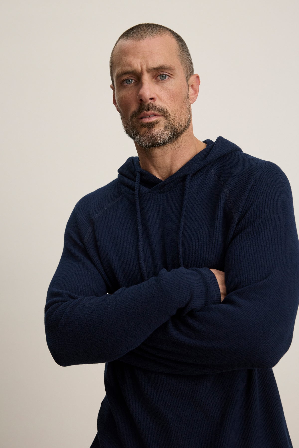 Man with short hair and beard wears the Velvet by Graham & Spencer ROMEO HOODIE, a relaxed fit pullover, standing with arms crossed against a plain light background.-39957110751425