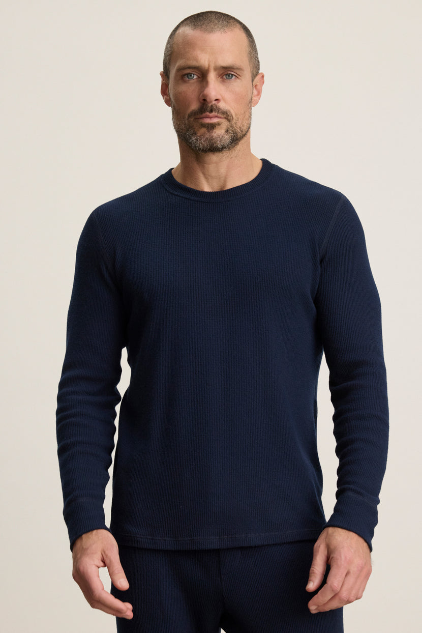 A man with short hair and a beard wears the TOBIAS CREW by Velvet by Graham & Spencer, a fitted long-sleeve navy classic crew, standing facing forward against a plain light background.