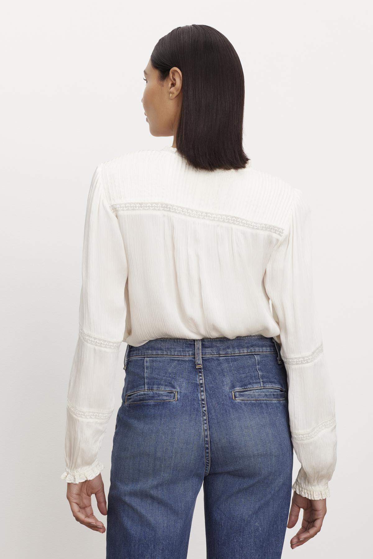   The view of a woman wearing jeans and a KOREN V-NECK BLOUSE by Velvet by Graham & Spencer. 