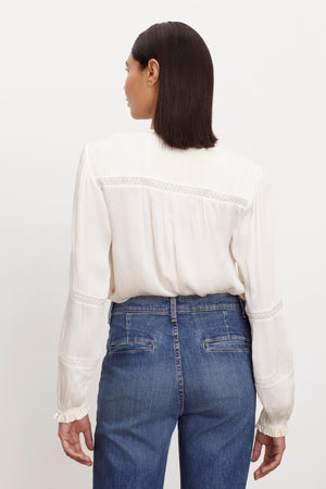 The view of a woman wearing jeans and a KOREN V-NECK BLOUSE by Velvet by Graham & Spencer.