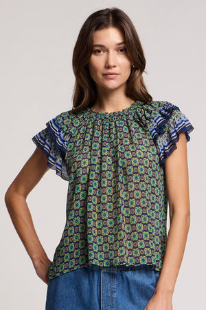 A woman wears the DAHLIA TOP by Velvet by Graham & Spencer—a short-sleeve crinkled viscose blouse with ruffled sleeves—paired with blue jeans, standing against a plain background.