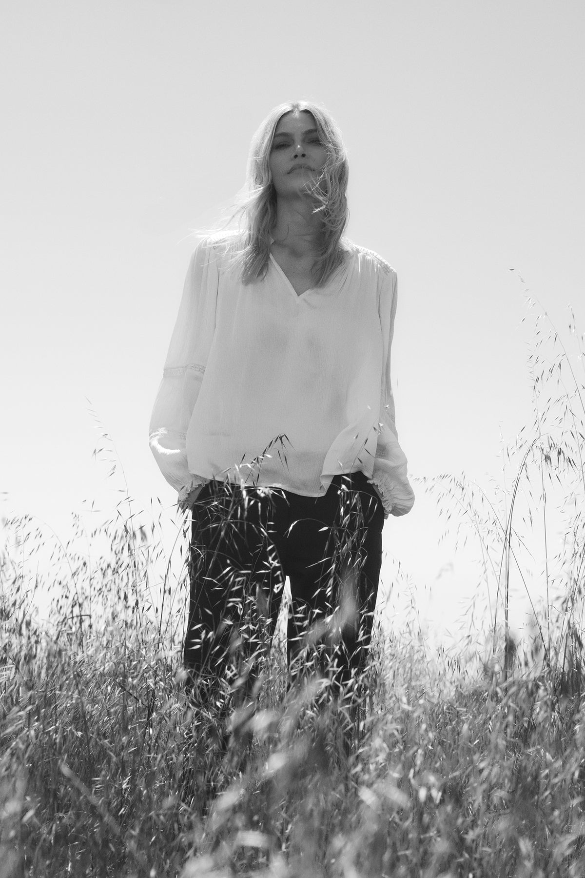 A photo of a woman wearing the Velvet by Graham & Spencer KOREN V-NECK BLOUSE and standing in tall grass.-35624025129153