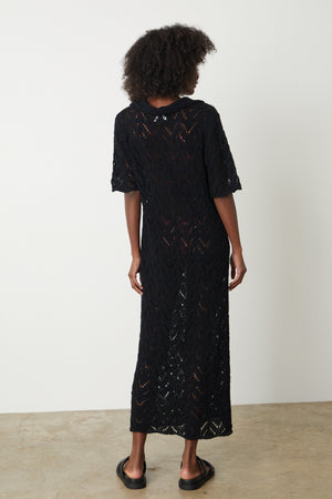 The back view of a woman wearing a Velvet by Graham & Spencer JACQUELINE CROCHET STITCH MAXI DRESS.